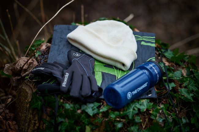 Eine Mütze, Stirnband und Getränkeflasche liegen auf dem Waldboden.