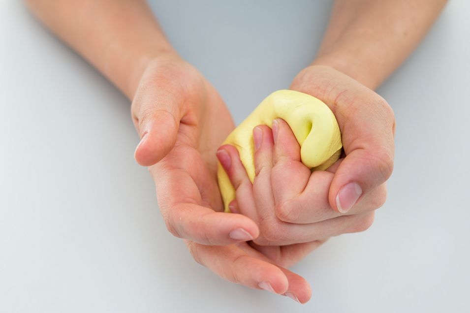 Nahaufnahme einer Patientin, die ein Knetobjekt mit der linken Hand knetet.