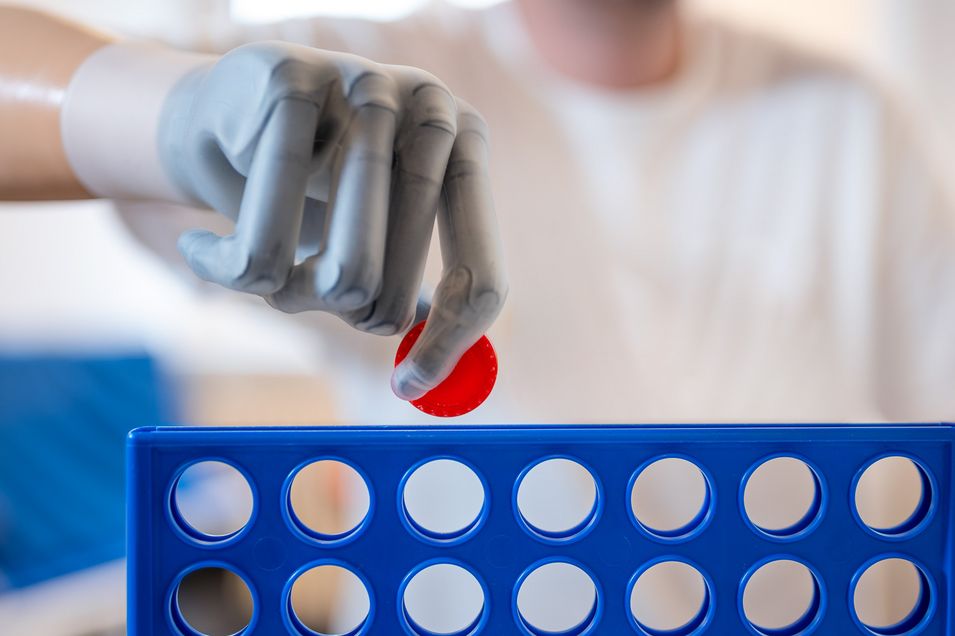 The patient plays the game "Connect Four" and plays his red token with his prosthetic hand.