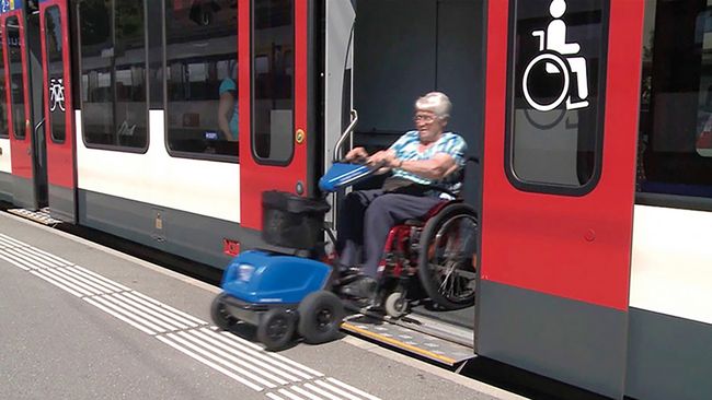 Mobil im öffentlichen Verkehr unterwegs. Frau im Rollstuhl steigt aus dem Zug aus.