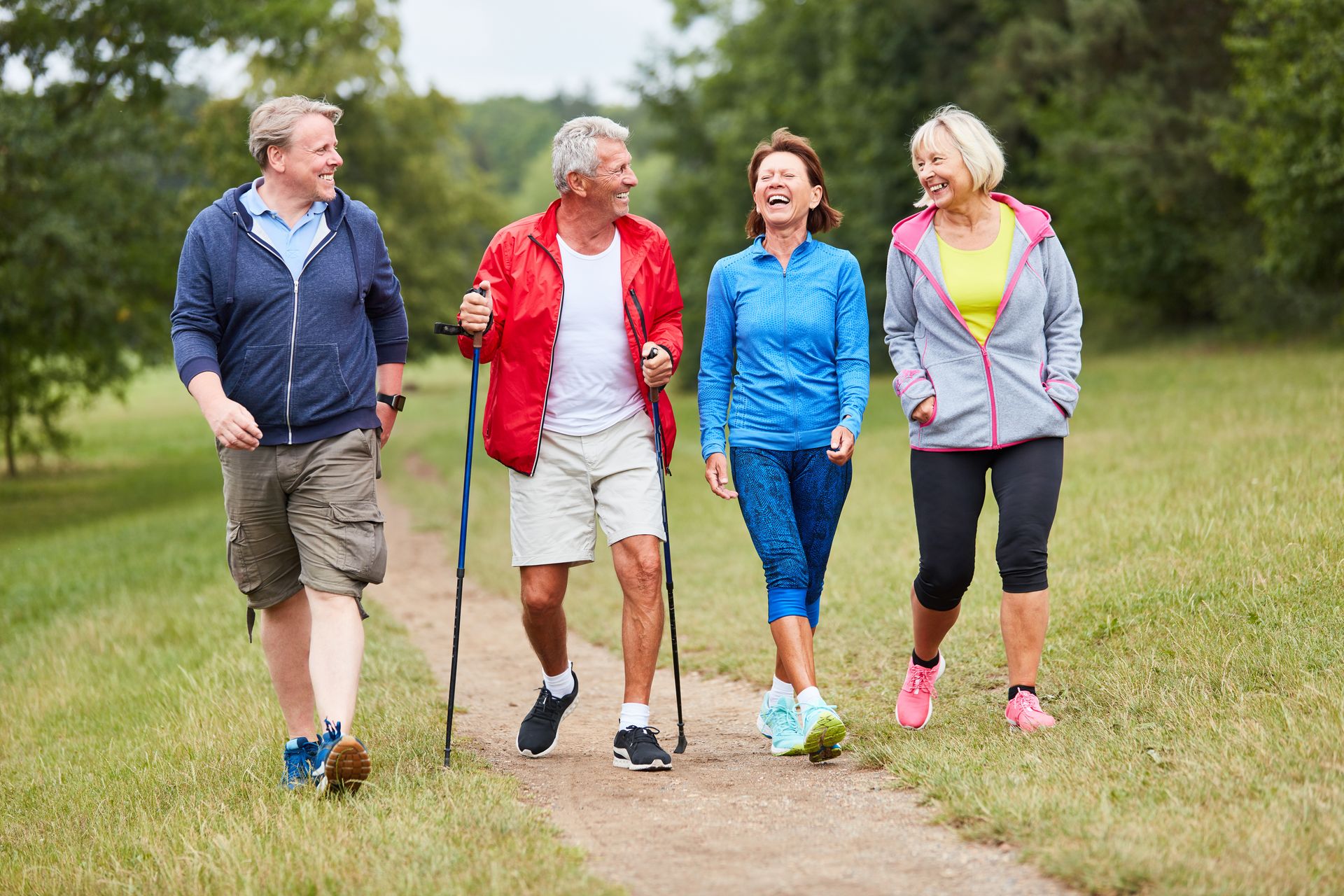 Eine Gruppe von vier Seniorinnen und Senioren unterhält sich während dem Wandern durch den Wald.