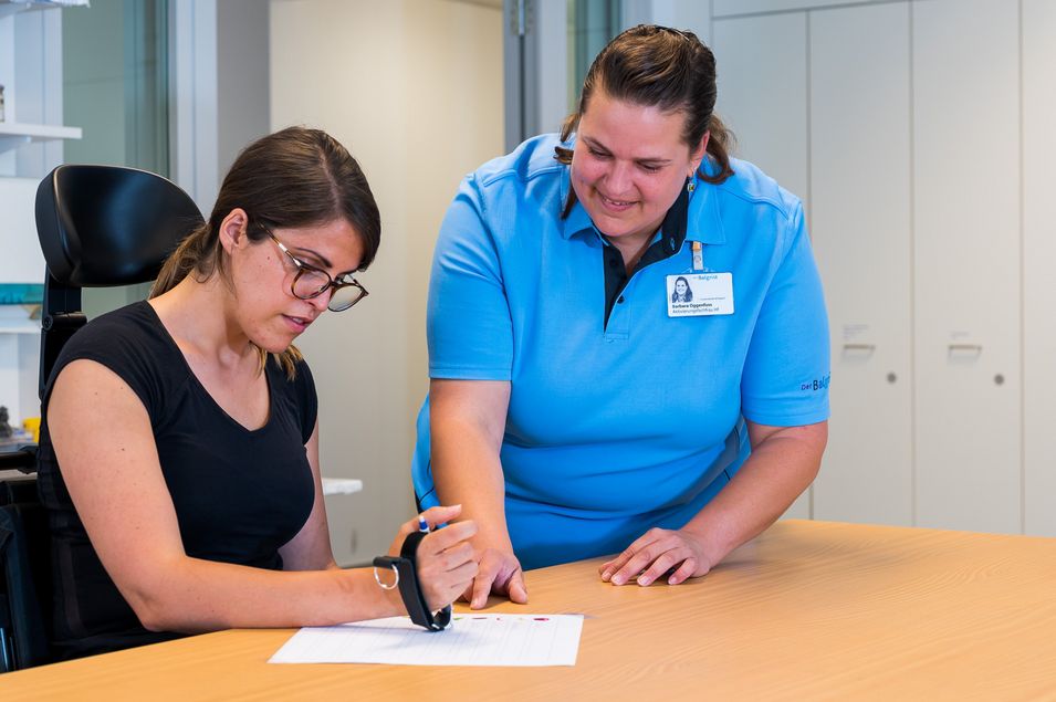 An occupational therapist assists the patient in relearning how to write.