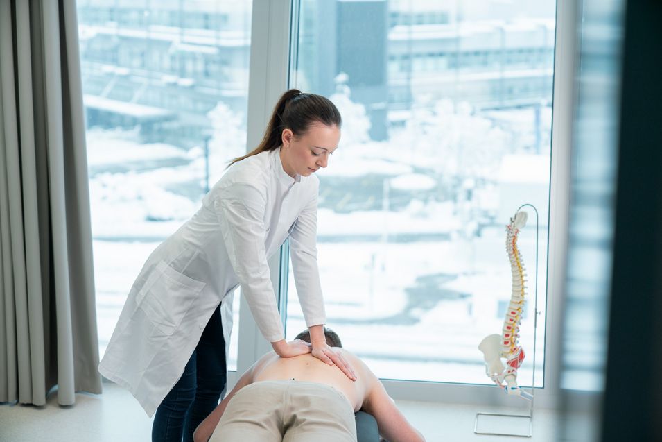 Chiropractor performs a spinal manipulation on a lying patient.