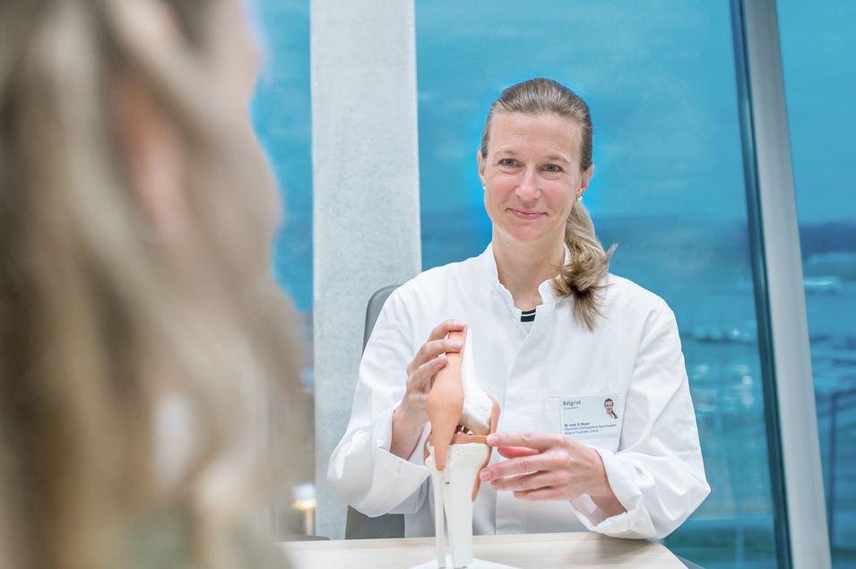 Orthopedist explains her complaints to a patient using a shoulder model.