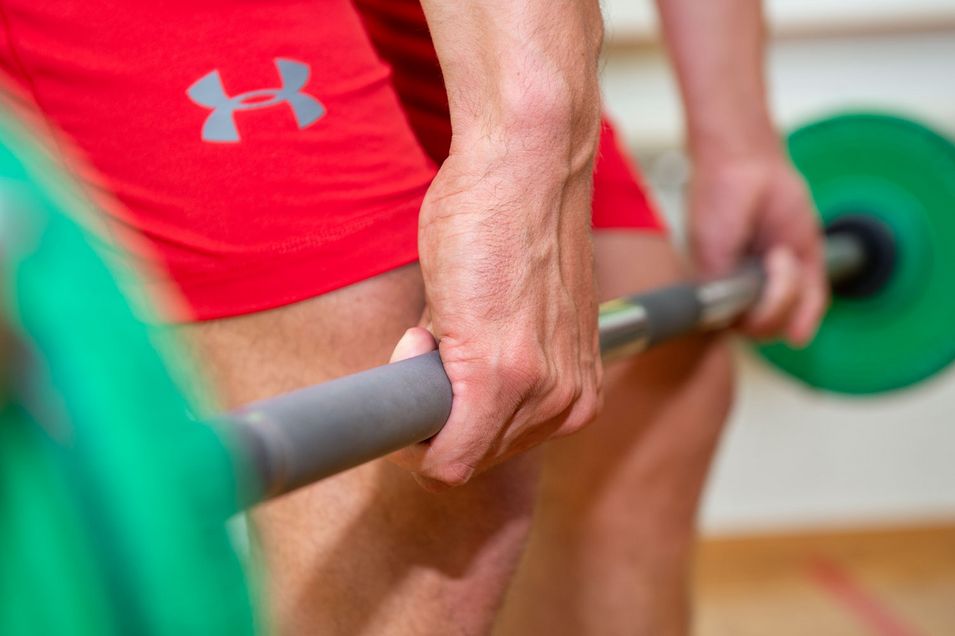 Close-up of a barbell held just above the knees.