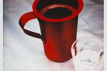 Rote Tasse auf einem weissen Tischtuch.