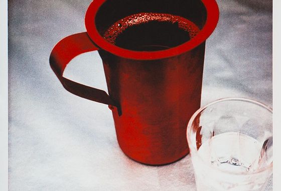 Rote Tasse auf einem weissen Tischtuch.