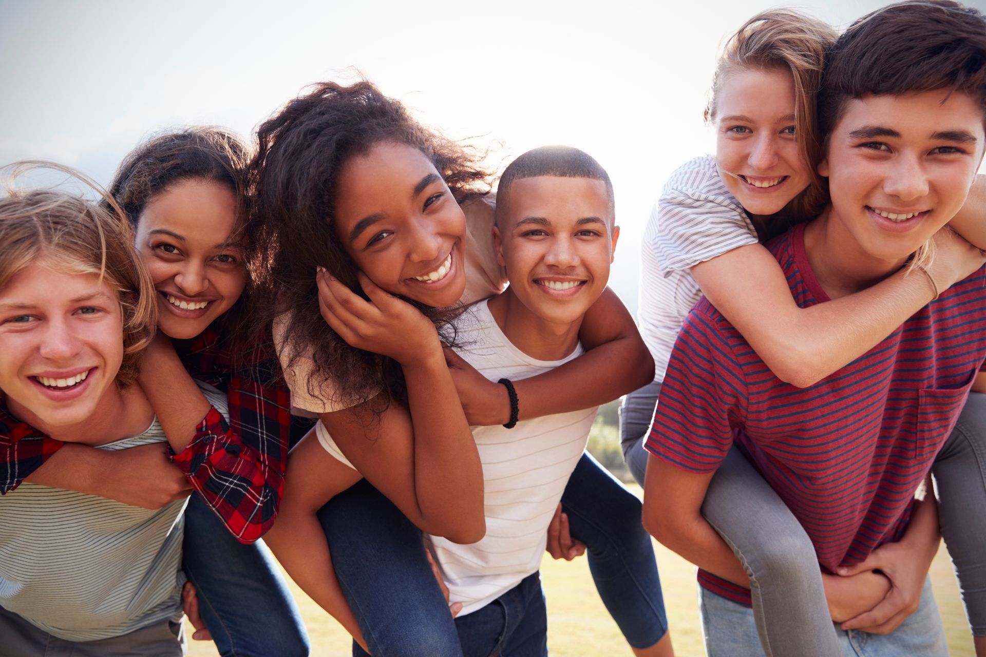 Eine Gruppe von sechs Jugendlichen lachen auf einem Gruppenfoto in die Kamera.