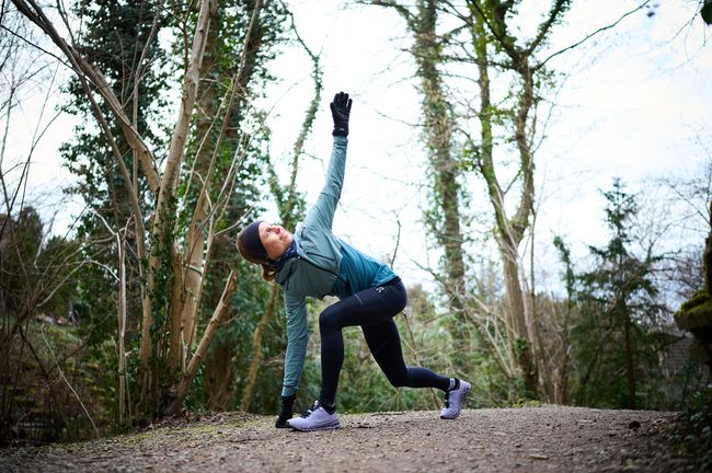 Joggerin wärmt sich auf einem Waldweg auf.