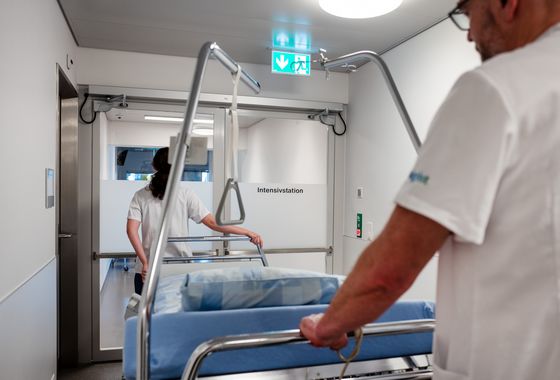 Zwei Mitarbeitende transportieren ein Patientenbett auf die Intensivstation.