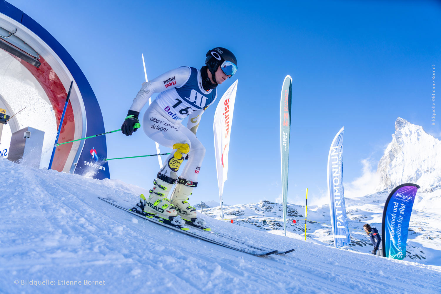 Ein Skifahrer startet seinen Lauf auf der Piste und betreibt Schneesport.