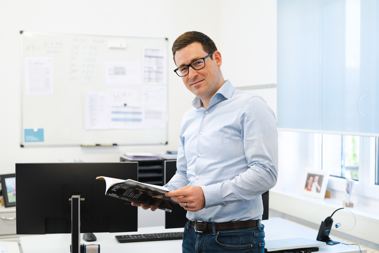 Sebastian Drews schlägt ein Magazin auf und steht in seinem Büro.
