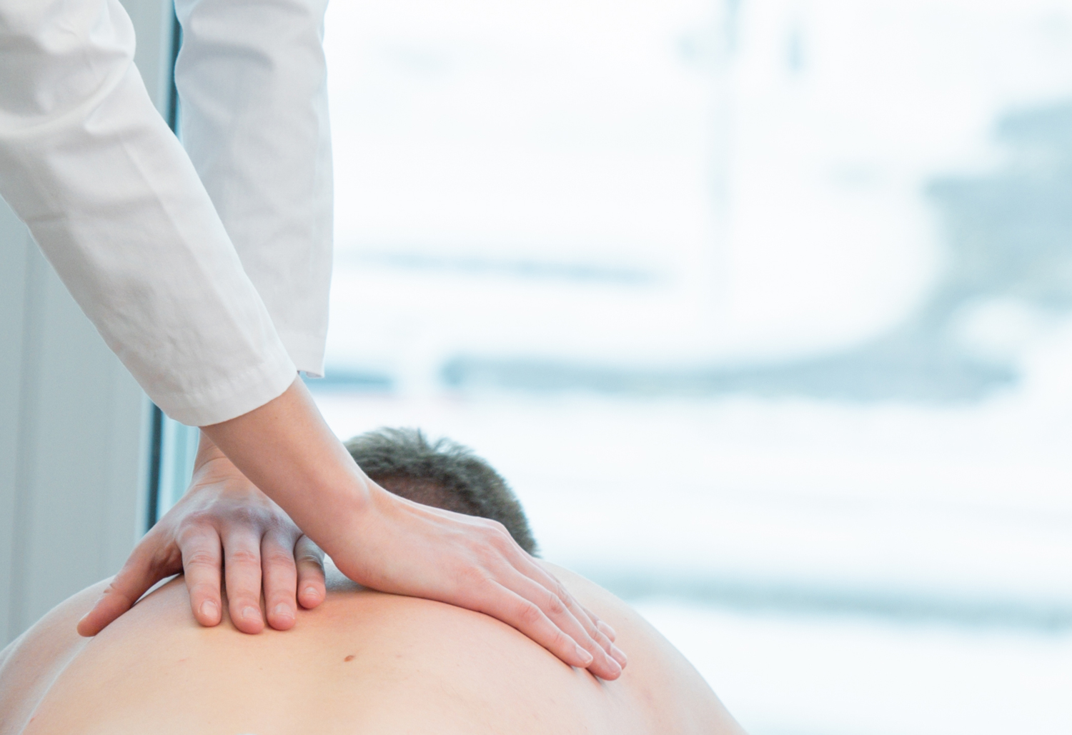 Hände auf dem Rücken eines Patienten bei einer chiropraktischen Behandlung 