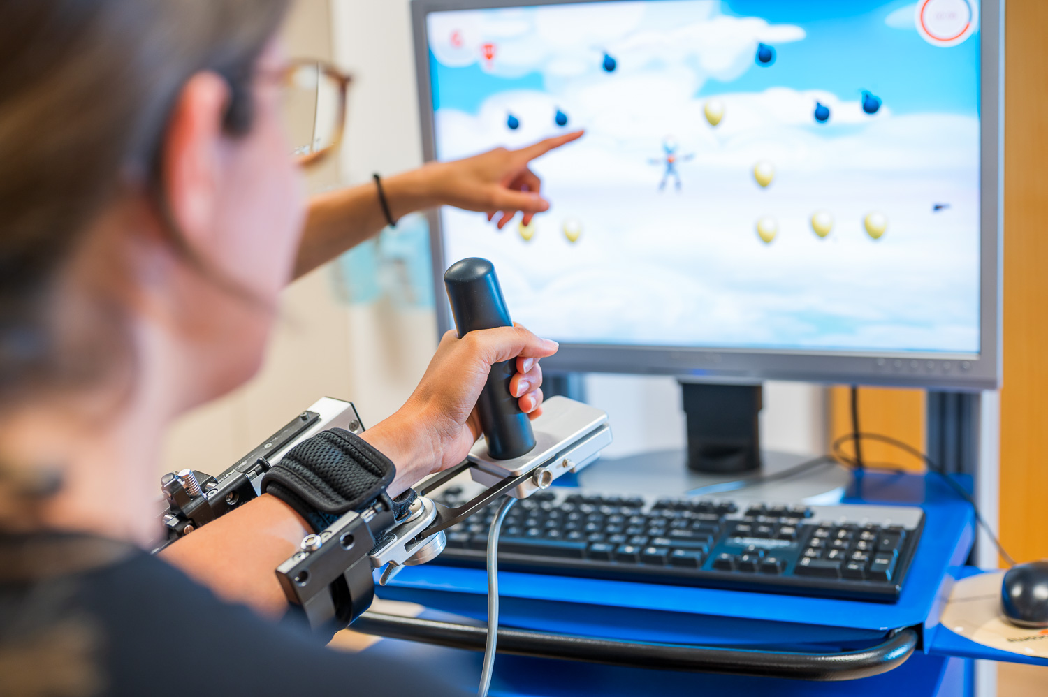 By means of playful tasks on the computer, the patient trains her hand and arm function.