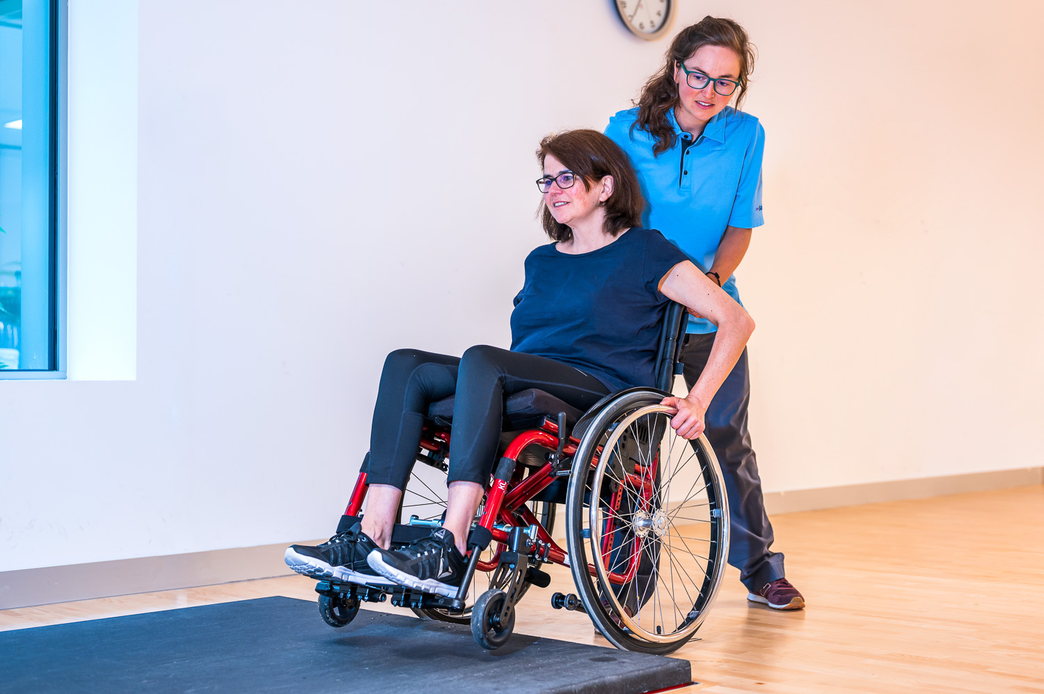 Occupational therapist overcomes a threshold on the floor with a patient in a wheelchair.