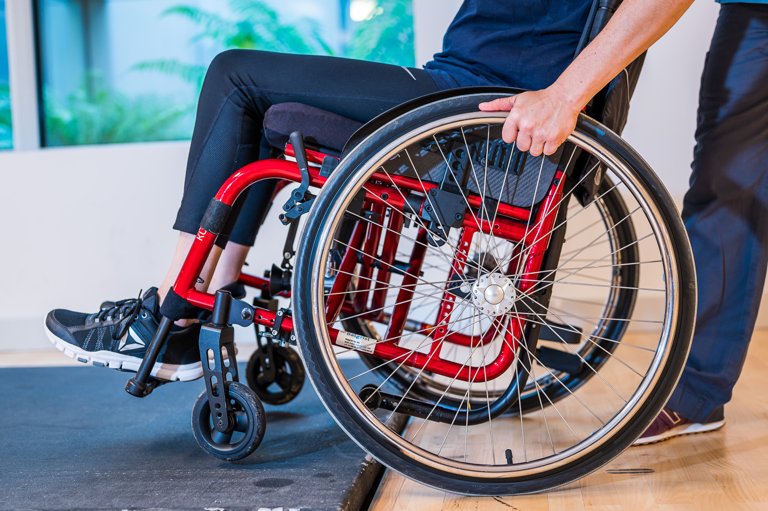 Close-up of a wheelchair with a hand operating the wheel.