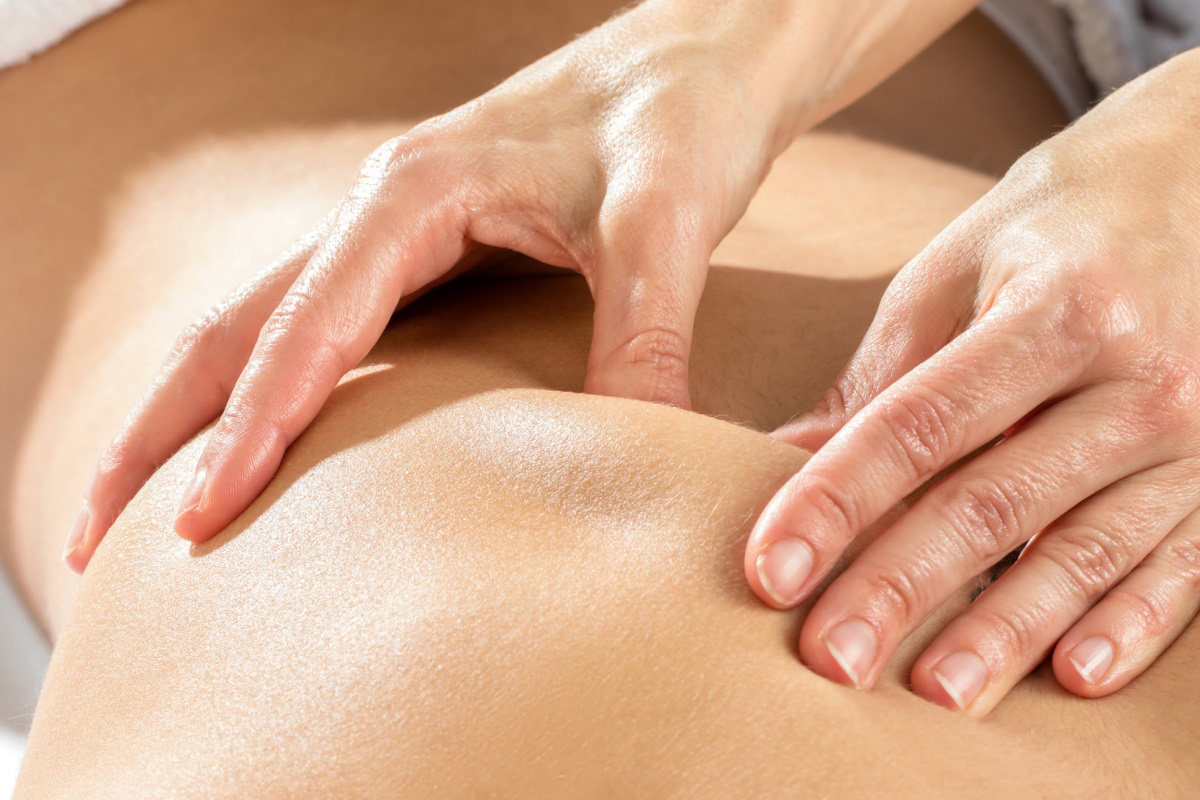 Two hands massage a back.