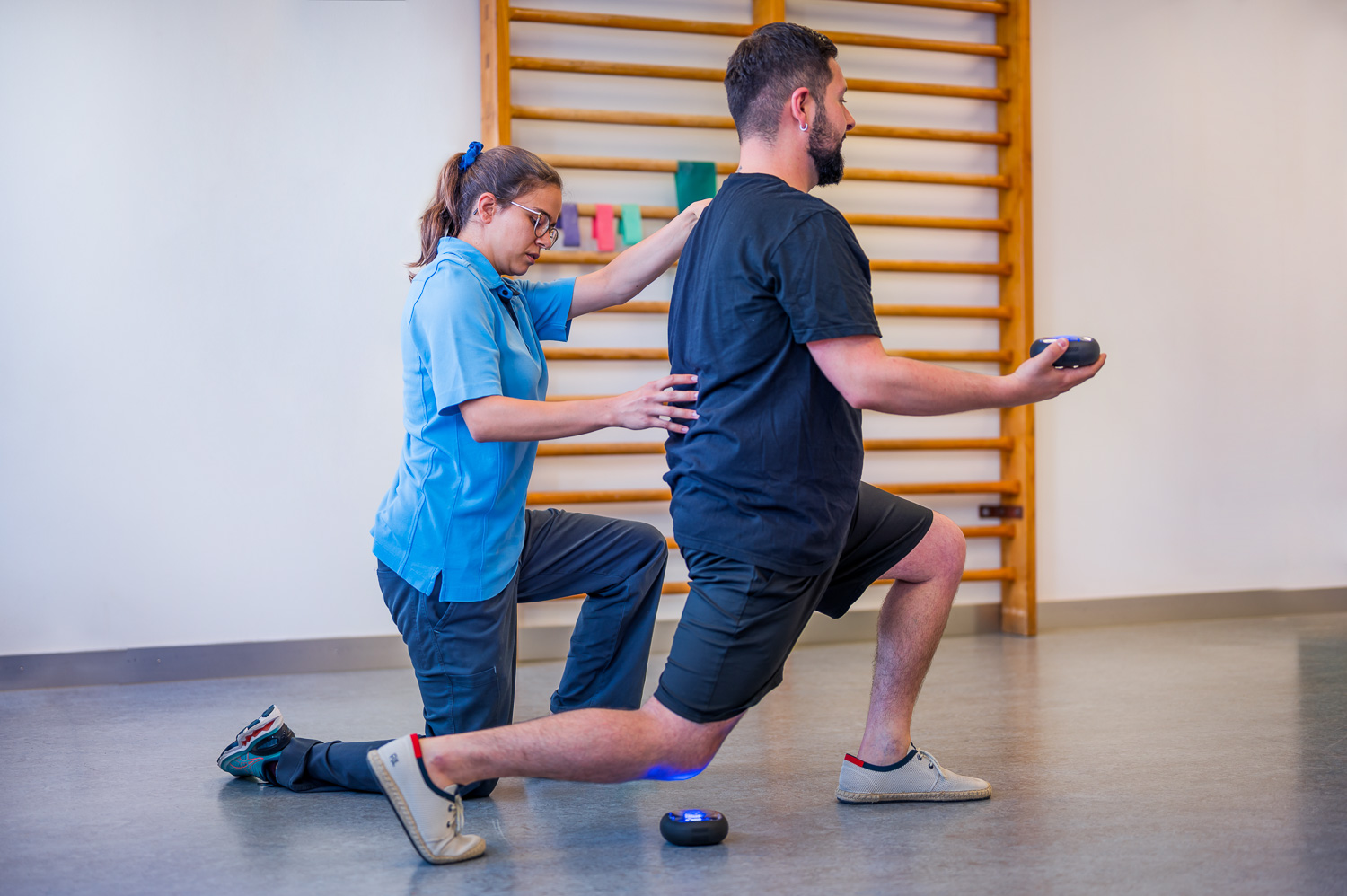 The physiotherapist pays attention to the correct posture of the patient during the lunge.