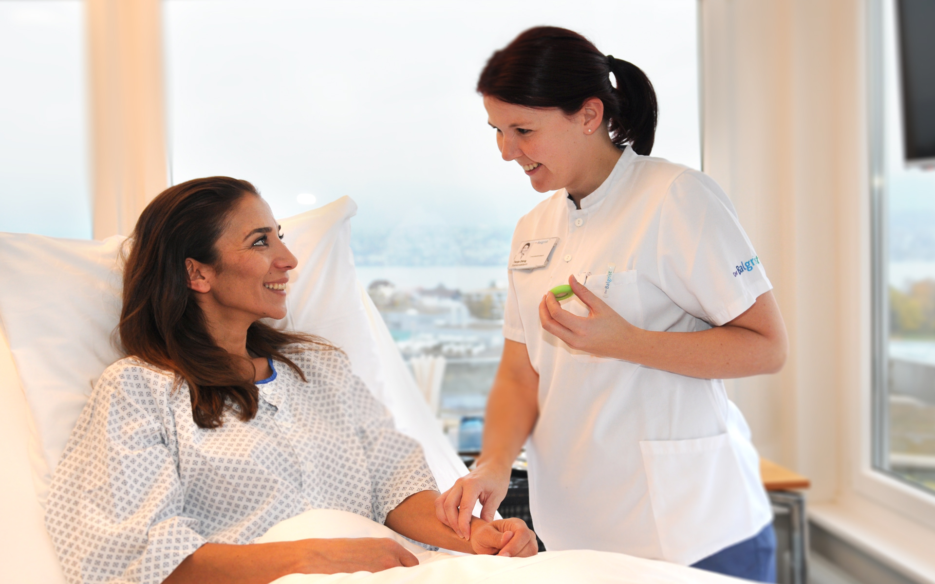 A nurse takes the pulse of a patient lying in bed.